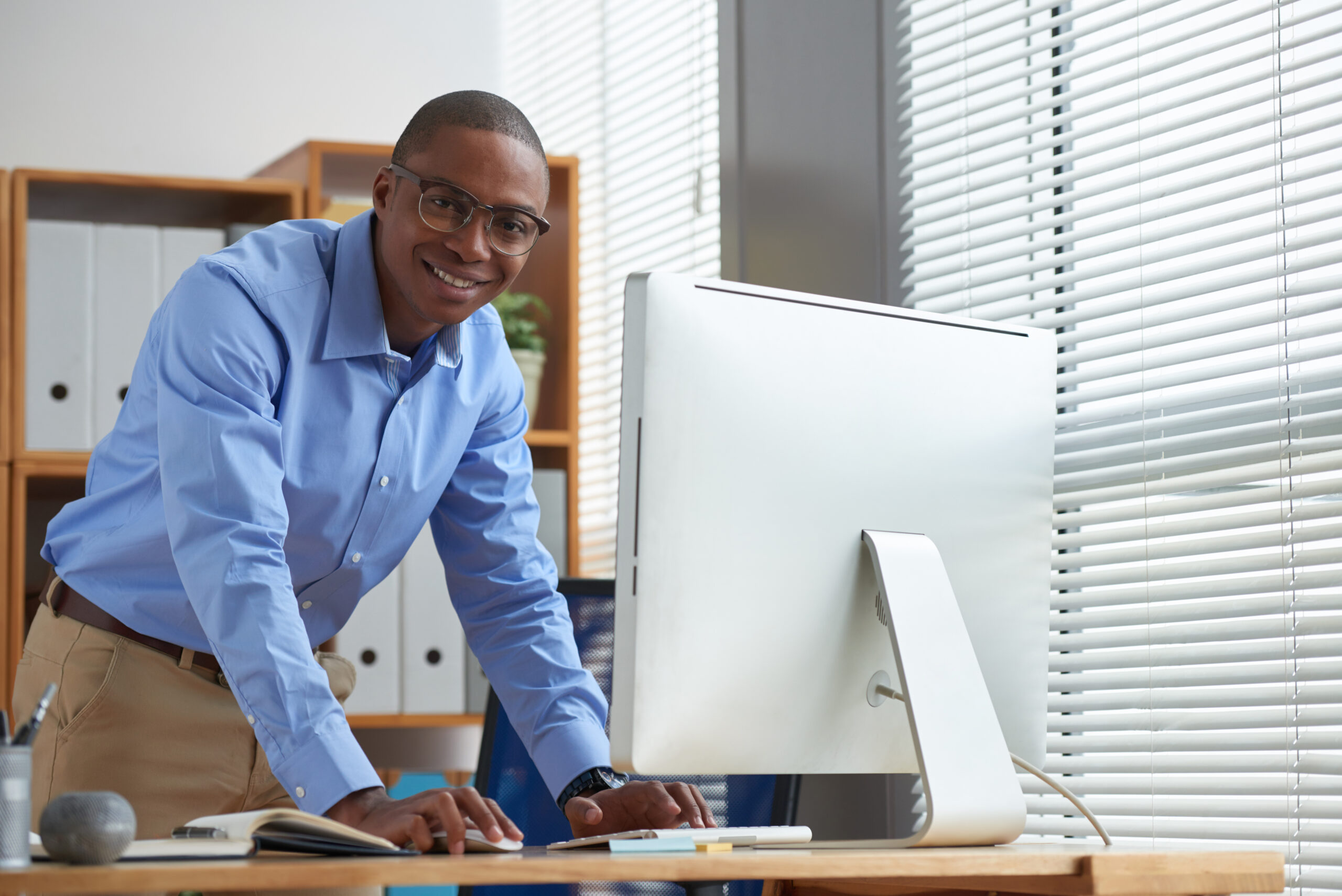 Cheerful entrepreneur searching something on computer and looking at camera